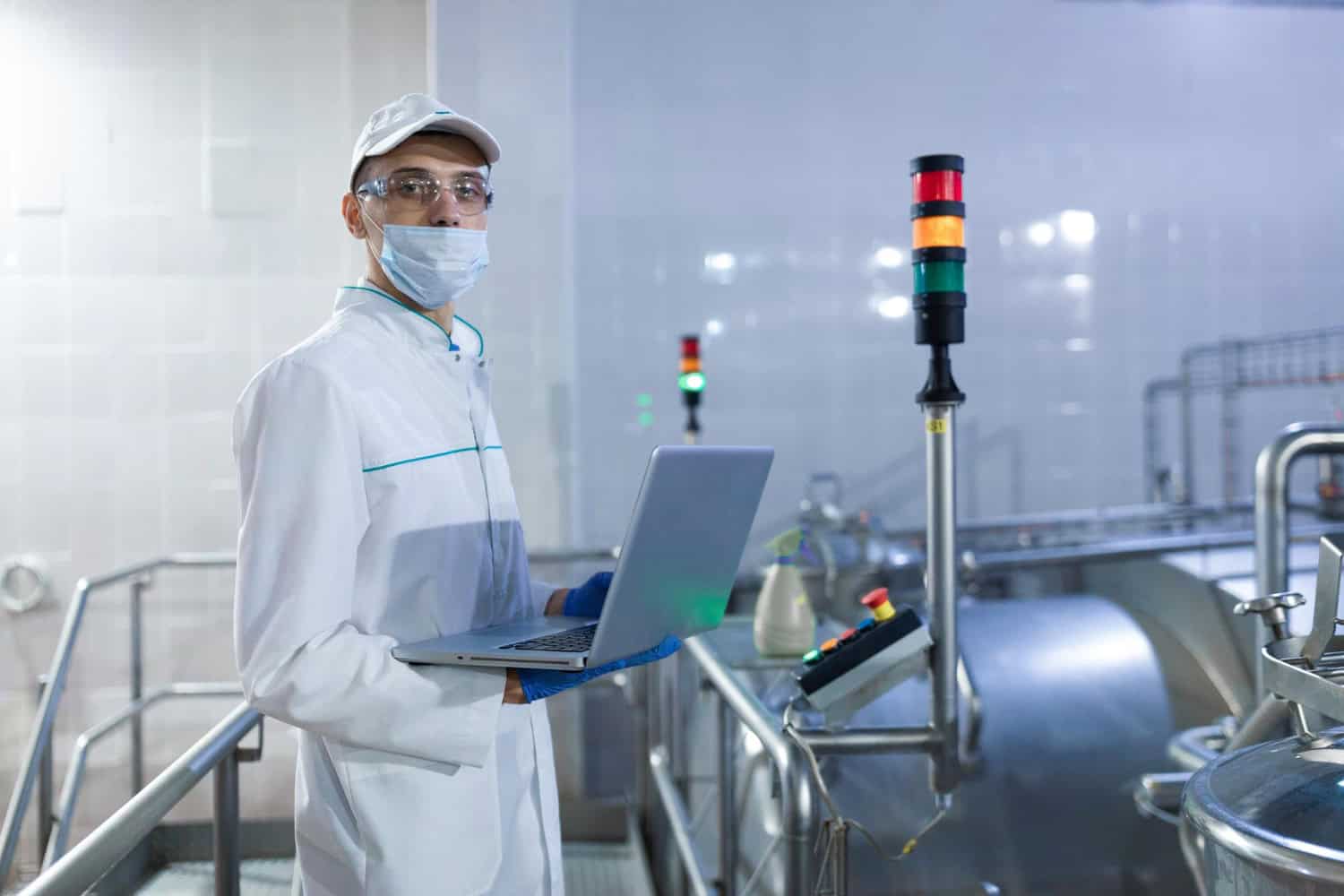 technologist with laptop his hands make set up production line while standing department dairy factory